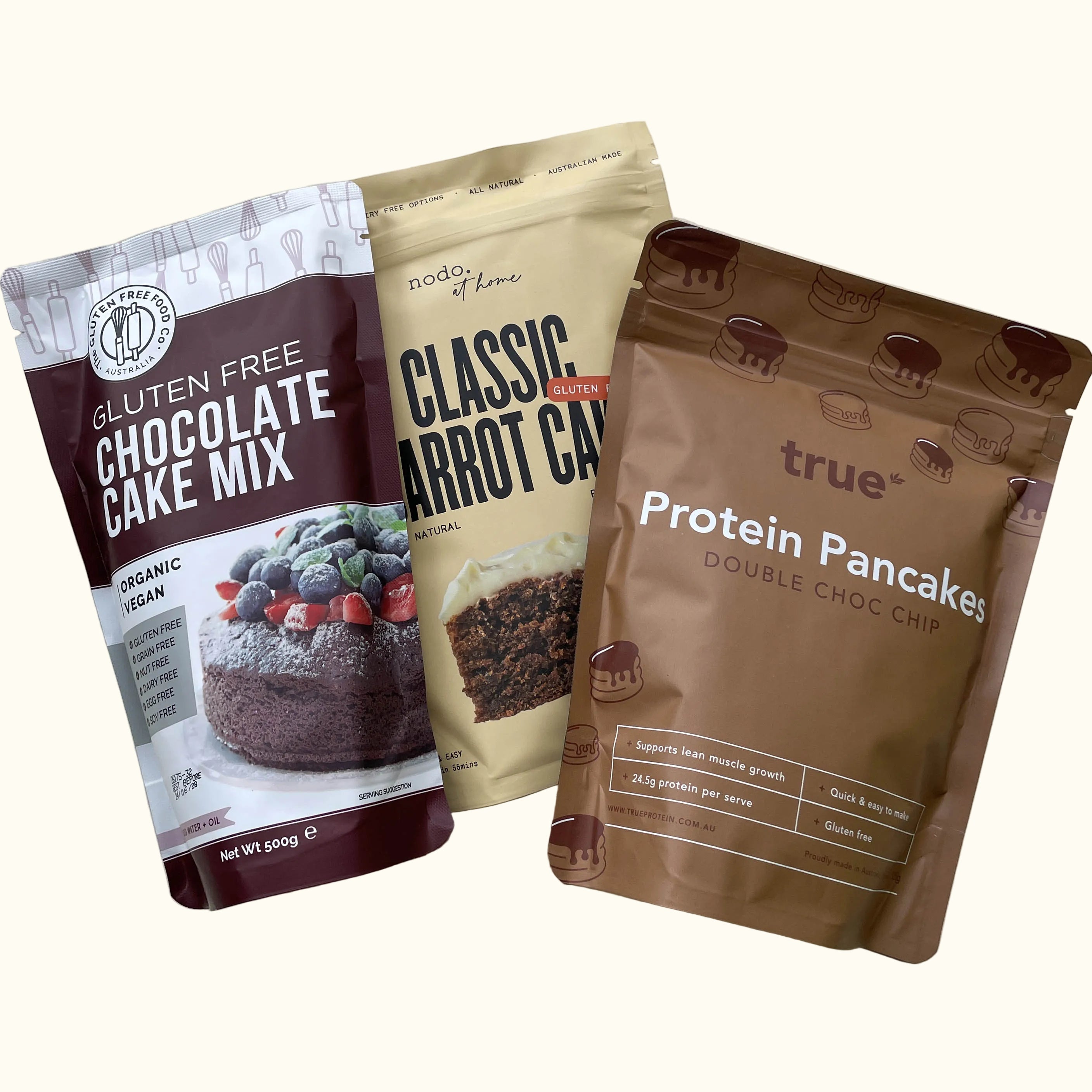 a dark chocolate cake mix pouch on the left, a classic carrot cake pouch in the center, and a protein pancakes double chocolate pouch on the right.
