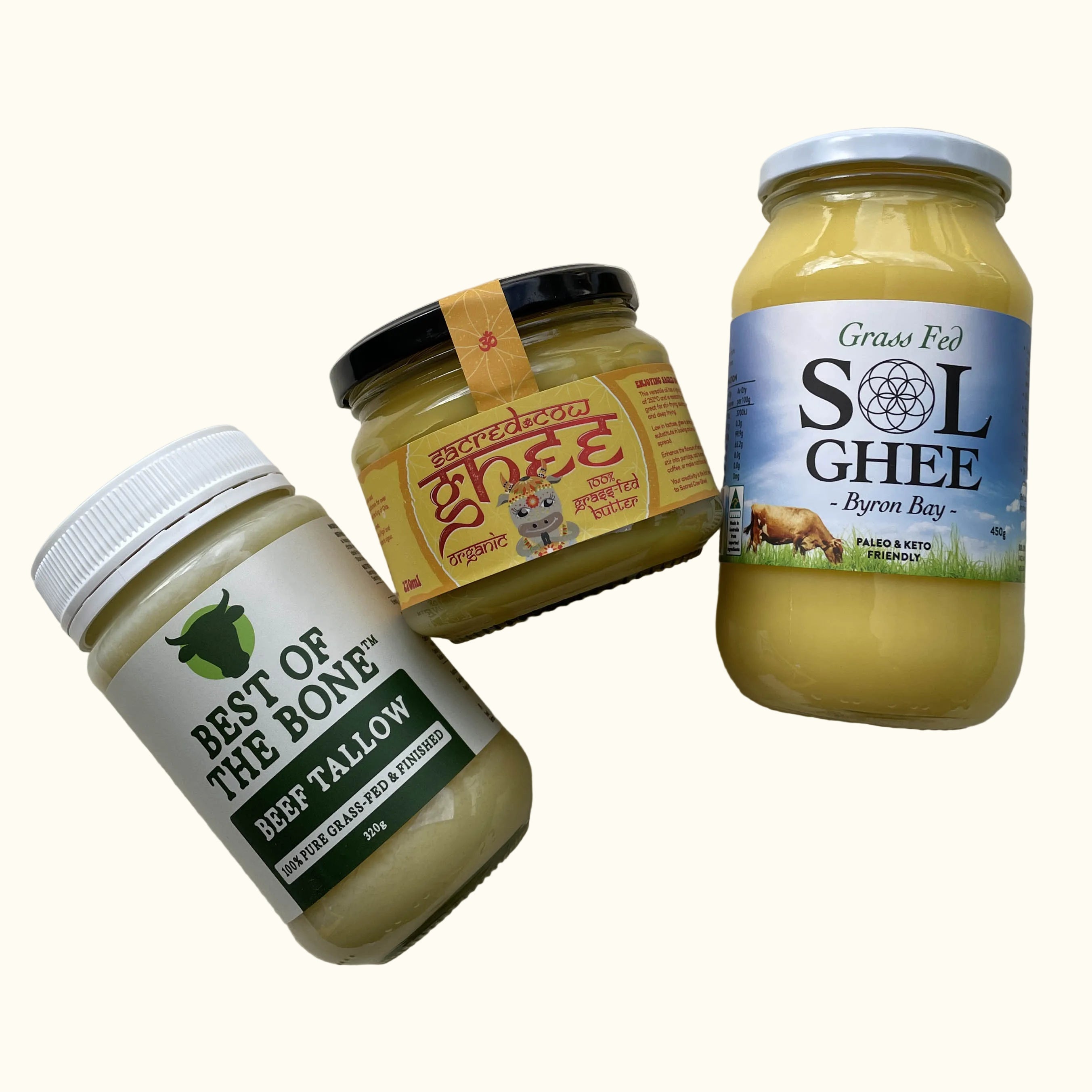 Three jars of Australian ghee and beef tallow arranged on a light wood background: Best of the Bone Beef Tallow, Ghee Organic Raw Unfiltered Ghee, and Grass Fed Sol Ghee.
