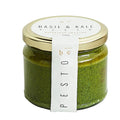 Jar of basil and kale pesto with a gold lid and white label on a white background
