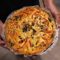 A whole Greensmith Kitchen ham, tomato and basil tart, golden from the oven and scattered with pepitas.