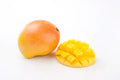 Whole and sliced mangoes on a white background